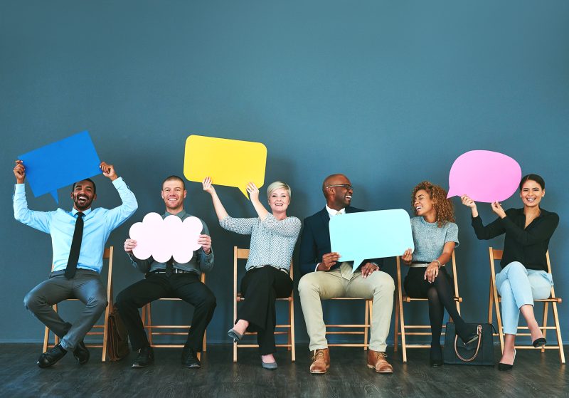Shot of a group of people holding up speech bubbles against a blue background